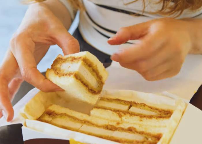 A vending machine tonkatsu sandwich. Shizuka is picking one quarter out of a little box.